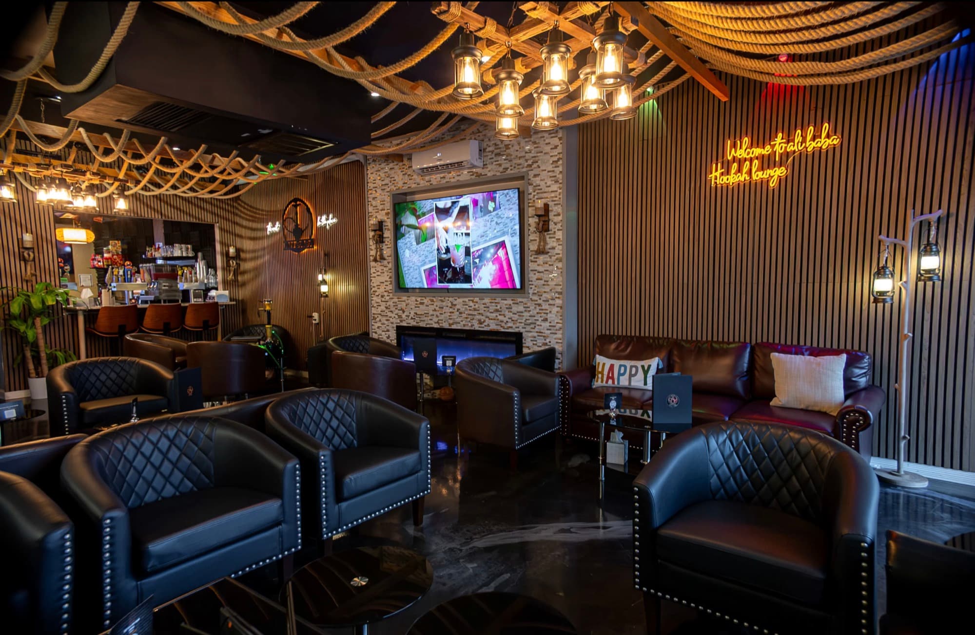 Lounge seating with a wall TV, fireplace and neon Alibaba sign