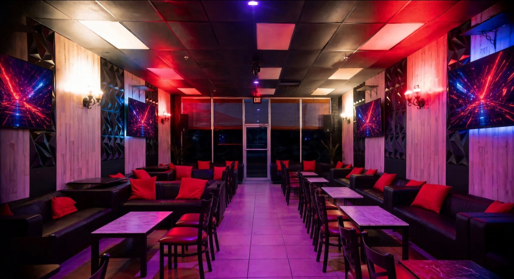 Lounge hall lit in red and violet with wall TVs and rows of leather sofas